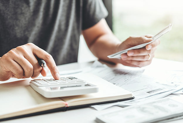 Close-up of a person analyzing financial documents and using a calculator, illustrating the process of the process of manual cash management.