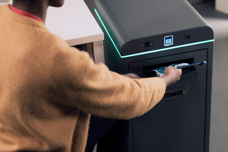 A retail employee makes a deposit into a Brink's Box.